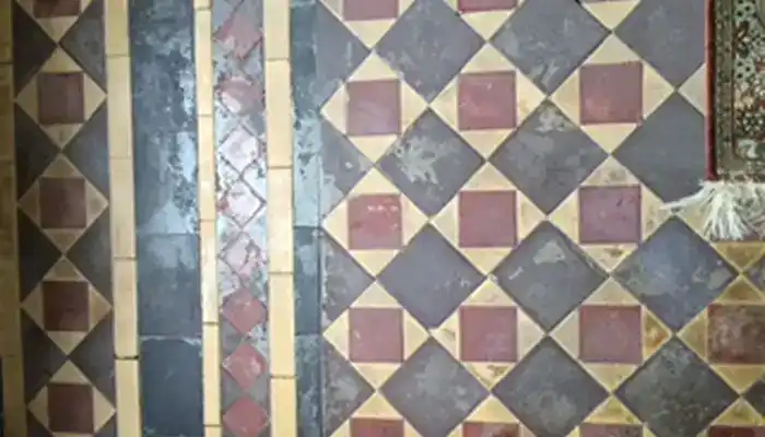 Dark residue-covered Minton tile hallway floor in Ovington before restoration