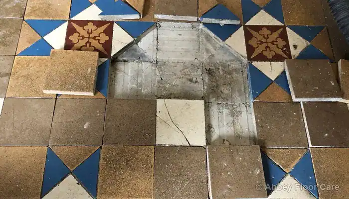 Loose Victorian tile lifted to show fractured screed and unstable bedding beneath