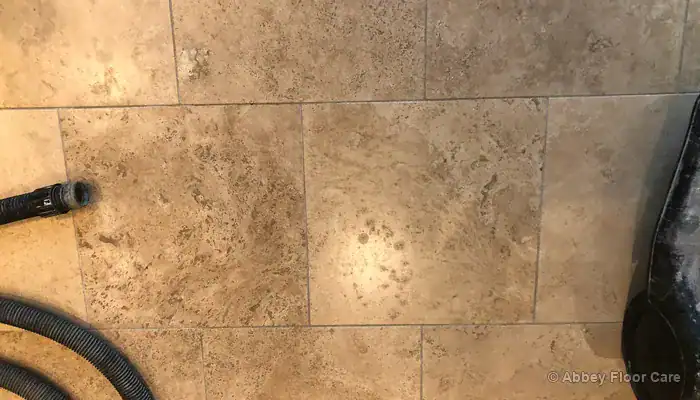 Close-up of dark soiled grout lines between beige travertine tiles