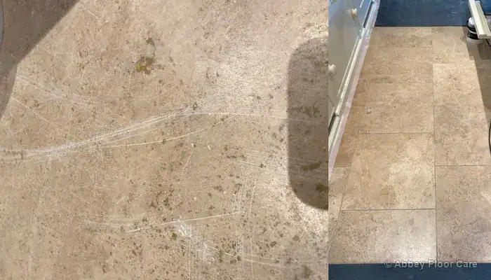 Before restoration: Worn travertine kitchen and dining room floor with dull traffic lanes, dark soiled grout lines, light scratches, and open holes with missing filler